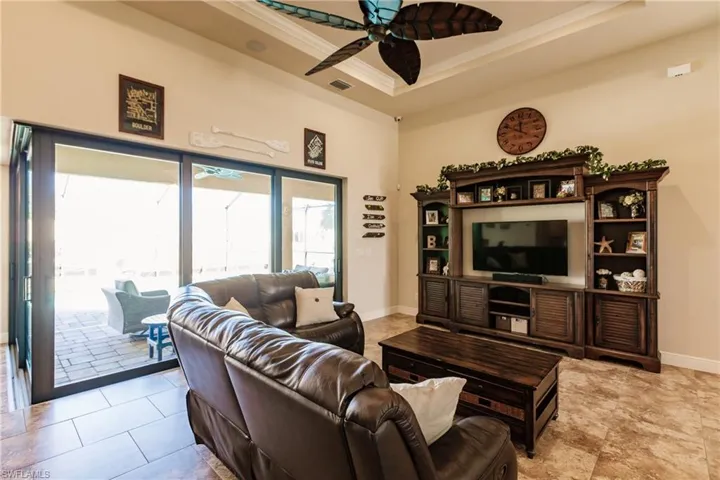 Tiled living room featuring ceiling fan and a raised ceiling