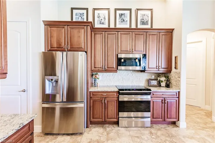 Kitchen featuring tasteful backsplash, light stone countertops, and appliances with stainless steel finishes