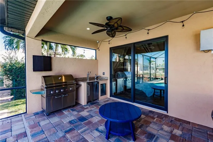 Covered outdoor living area includes kitchenette with granite countertop and sink.