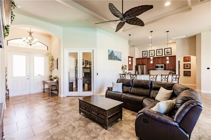 Living room with a high ceiling, ornamental molding, a raised ceiling, and ceiling fan