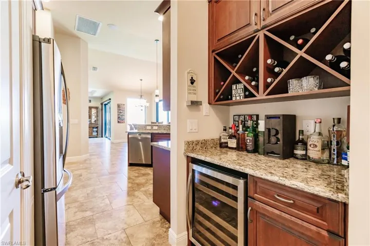 Butler's pantry/bar with light tile patterned flooring, appliances with stainless steel finishes, and wine cooler