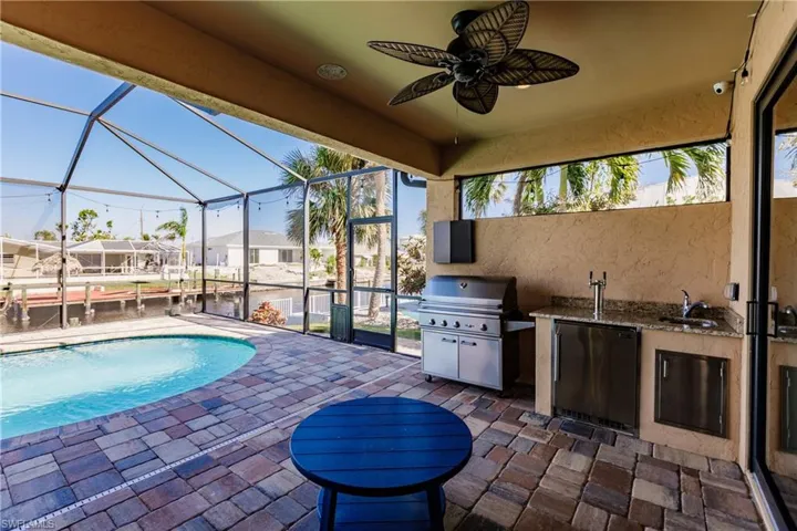 Covered outdoor living area includes kitchenette with granite countertop and sink.