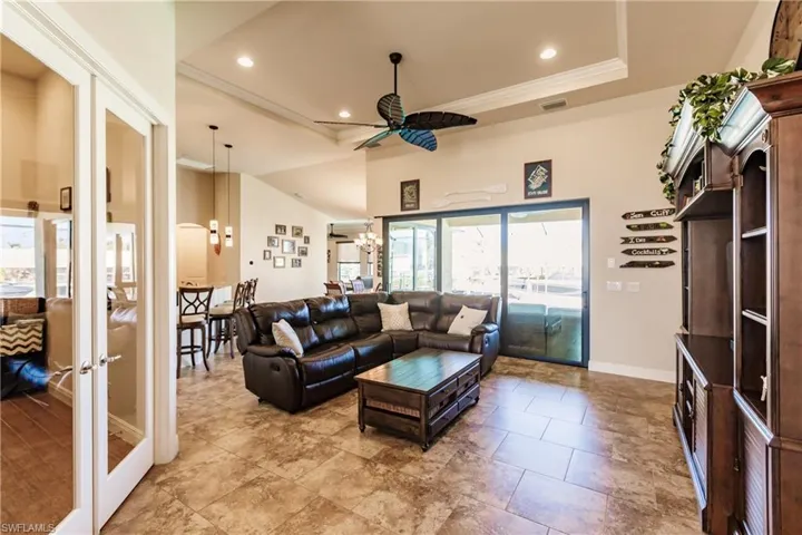 Living room featuring a raised ceiling, ornamental molding, and ceiling fan