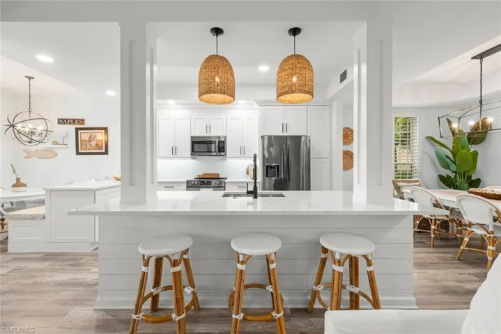 Kitchen featuring white shaker cabinetry, stainless steel appliances, quartz countertops, and luxury vinyl wood-finish flooring
