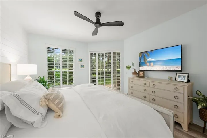 White shiplap accent wall, wood-finish flooring, and multiple windows with plantation shutters