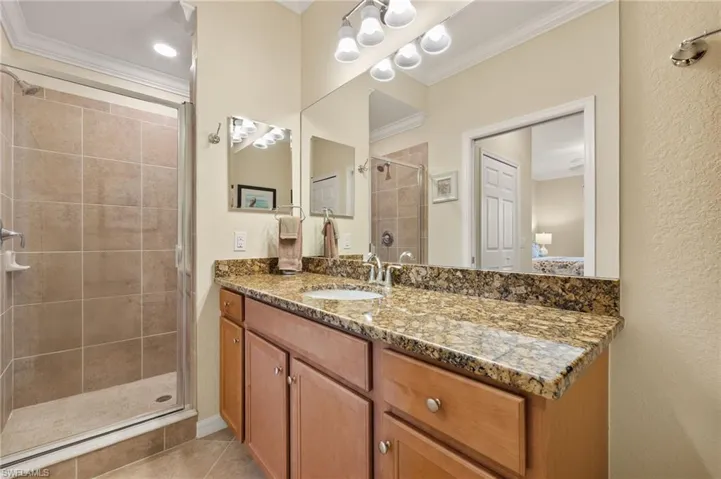 Full bath featuring ornamental molding, a stall shower, tile patterned flooring, and vanity