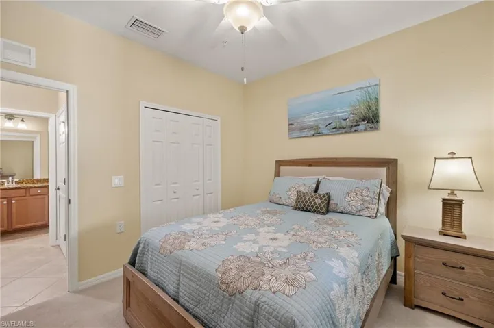 Bedroom featuring a closet, light carpet, baseboards, a ceiling fan, and light tile patterned floors