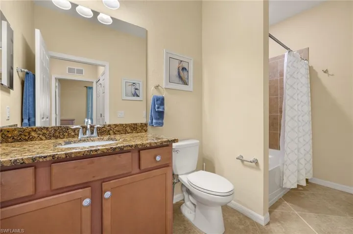 Full bathroom featuring toilet, vanity, tile patterned flooring, shower / bath combo with shower curtain, and baseboards
