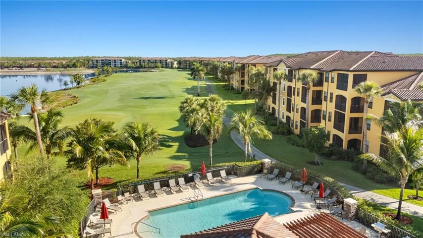 Community pool with a patio, view of golf course, and a water view