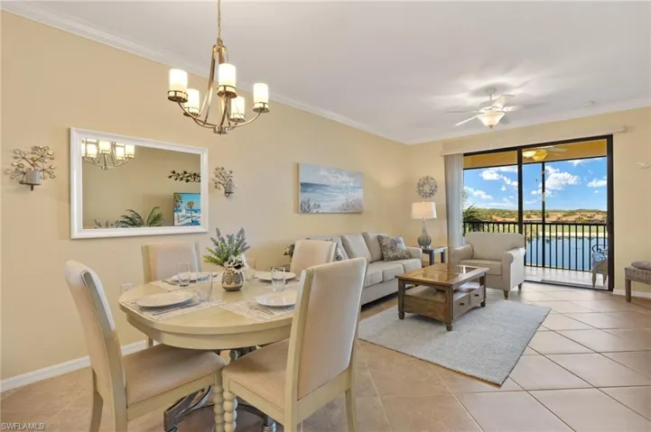 Dining room featuring light tile patterned floors, a chandelier, crown molding, baseboards, and a ceiling fan