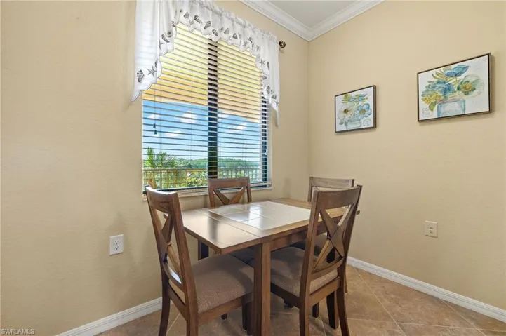 Tiled dining room with crown molding and baseboards