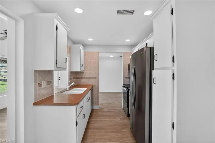 Kitchen featuring stainless steel appliances, white cabinets, light wood-style flooring, and recessed lighting