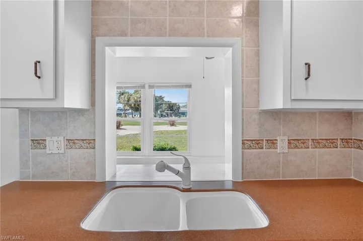 Kitchen featuring tasteful backsplash and white cabinetry