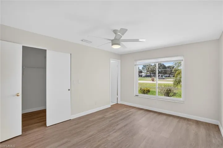Master bedroom with light wood-style floors, ceiling fan, and a walk in closet