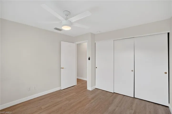 Unfurnished bedroom with light wood-style floors, a closet, and a ceiling fan