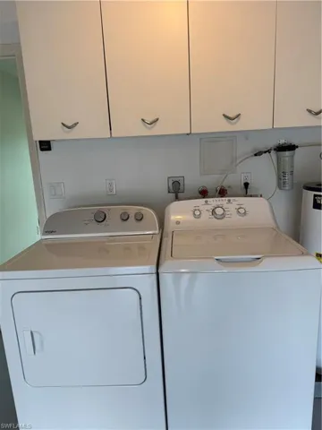 Laundry room with cabinet space, washer and clothes dryer, and water heater