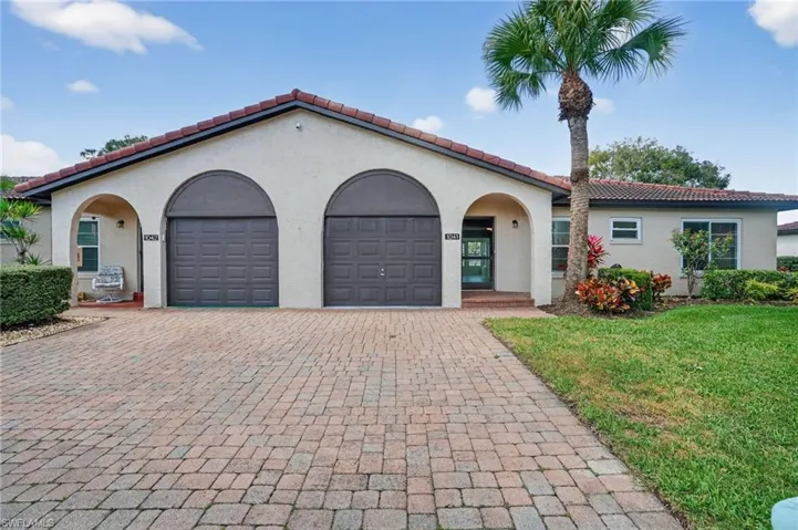 Mediterranean / spanish home featuring a garage, decorative driveway, a tiled roof, and stucco siding