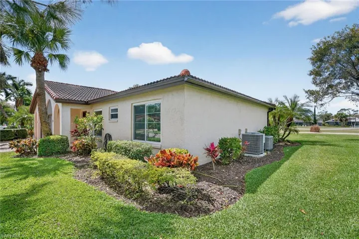 View of property exterior with a lawn, stucco siding, and a tiled roof