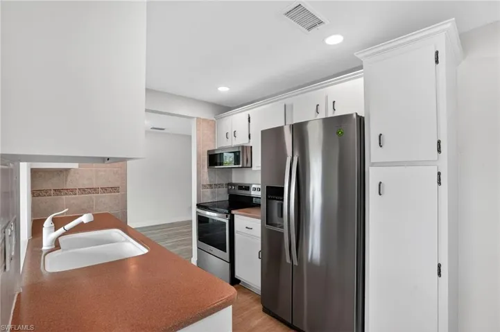 Kitchen featuring stainless steel appliances, light wood finished floors, white cabinets, and recessed lighting