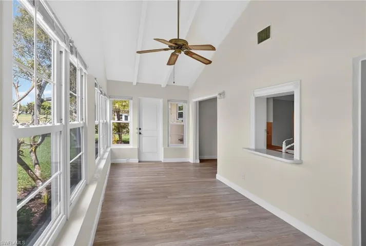 Unfurnished sunroom featuring vaulted ceiling and wood finished floors