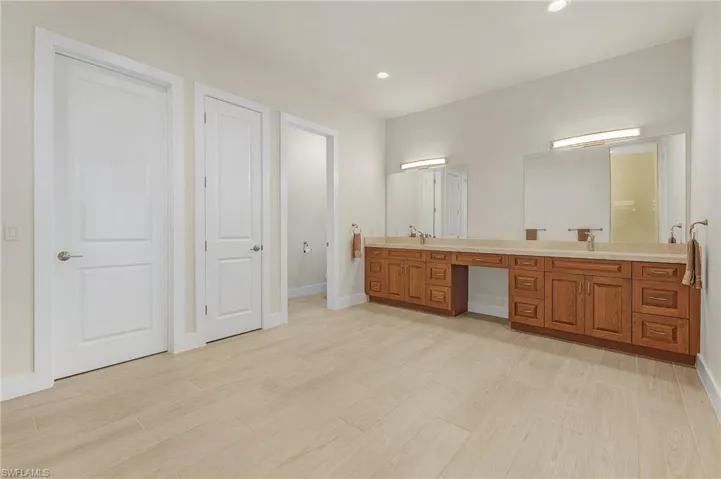 Primary Bathroom featuring dual vanities, walk in closet and tile floors