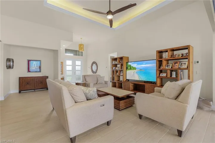 Living room with tile flooring, single coffered ceiling with crown moulding, and ceiling fan