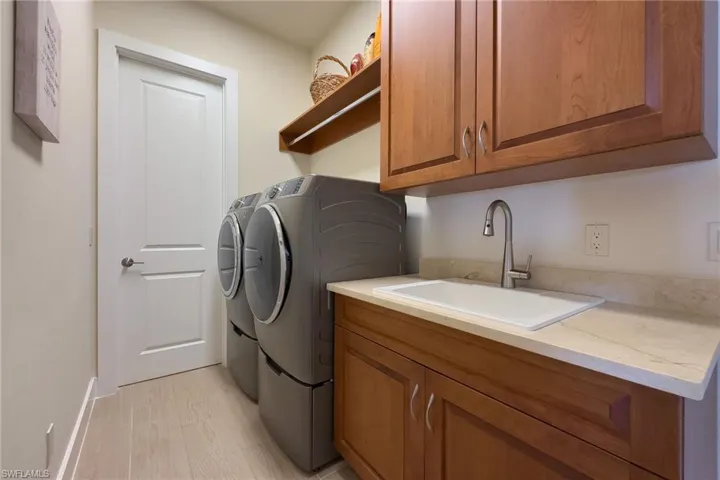 Laundry area with cabinets, washer, dryer, and utility sink