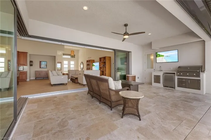Covered lanai featuring area for grilling, ceiling fan, screened enclosure and 90 degree sliders