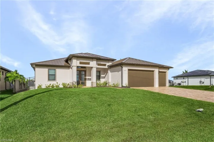 Front exterior featuring a three car garage, the front yard, and paver driveway