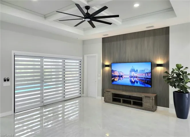 Living room featuring beamed ceiling, ceiling fan, and coffered ceiling