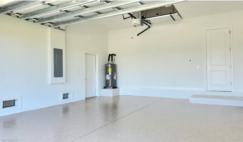 Garage with electric panel, water heater, and a garage door opener