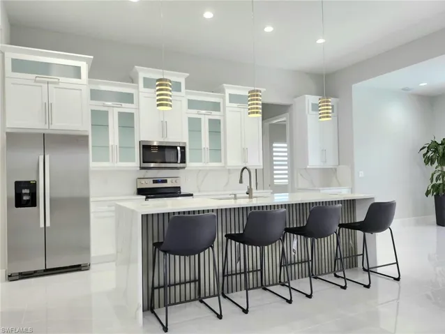 Kitchen with appliances with stainless steel finishes, pendant lighting, a breakfast bar, sink, and tasteful backsplash