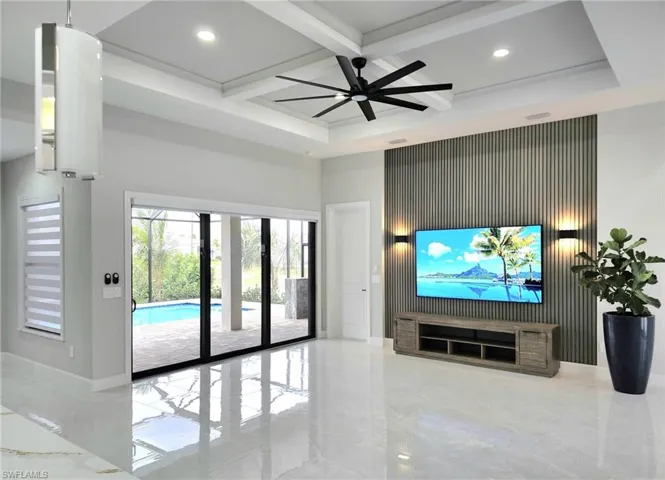 Living room with a high ceiling, beam ceiling, ceiling fan, and coffered ceiling