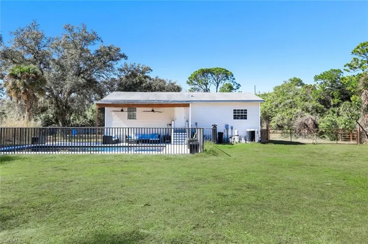 Rear view of house with a ceiling fan, a fenced backyard, a patio, and an outdoor pool