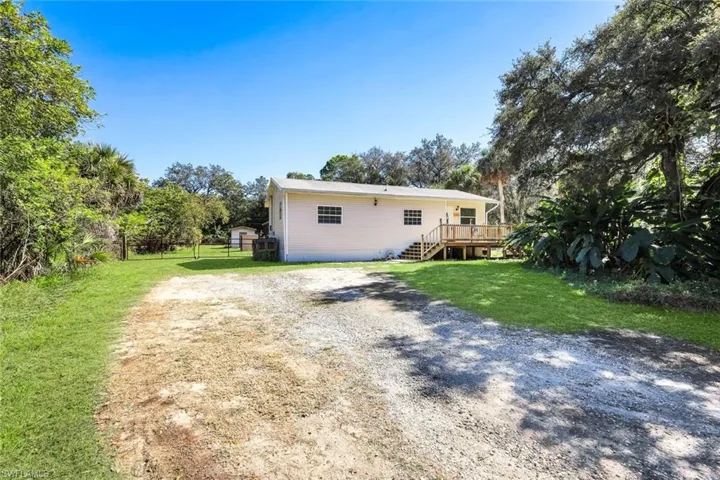 Back of house featuring a lawn, a deck, driveway, and stairway