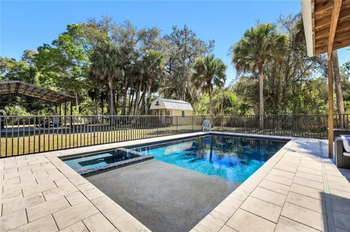 View of swimming pool featuring a pool with connected hot tub, a fenced backyard, and a patio area