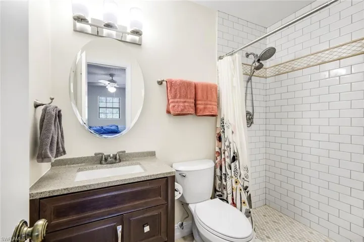 Full bathroom with vanity, a stall shower, and a ceiling fan