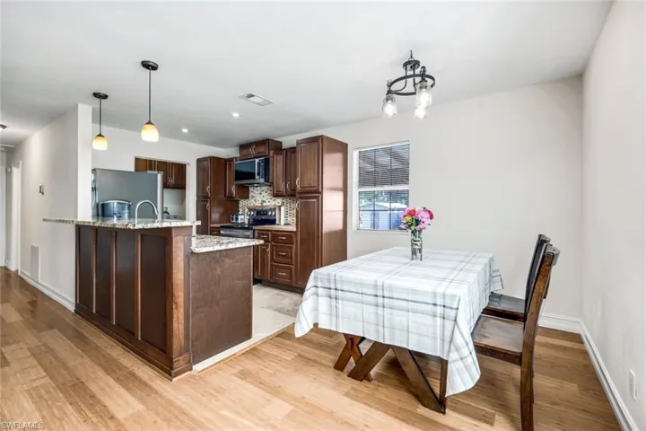 Kitchen featuring light stone countertops, dark brown cabinets, stainless steel appliances, tasteful backsplash, and light wood-style floors