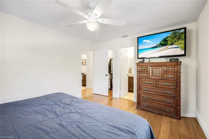 Bedroom with light wood-type flooring, ceiling fan, and a spacious closet