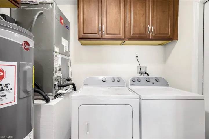 Laundry area with water heater, heating unit, cabinet space, and washing machine and clothes dryer