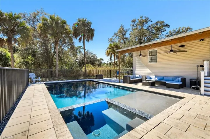 View of pool featuring a patio, a pool with connected hot tub, a fenced backyard, and an outdoor hangout area