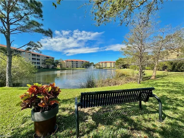 Landscaped grounds featuring a tranquil pond with a fountain, surrounded by manicured lawns and mature trees