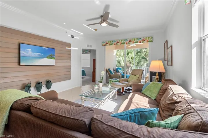 Living area featuring wood-finish accent wall, crown molding, and light tile flooring