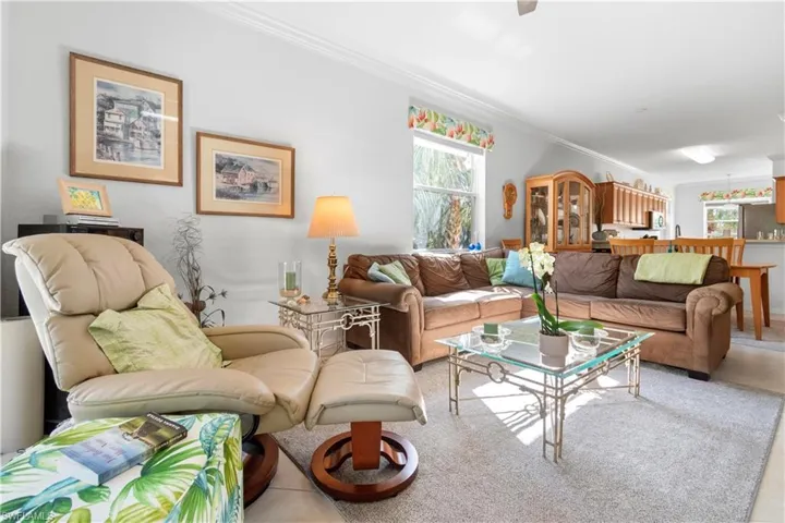 Open-concept living area featuring neutral wall paint, crown molding, and tile floors