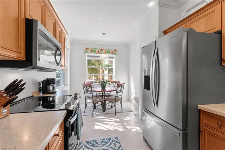 An eat-in kitchen featuring wood-finish cabinetry, light-toned countertops, and stainless steel appliances including a French door refrigerator and an over-range microwave
