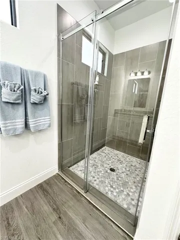 Full bathroom with a stall shower, wood finished floors, and a textured wall