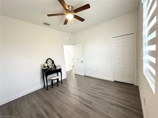 Bedroom featuring dark wood-style flooring, ceiling fan, and a closet