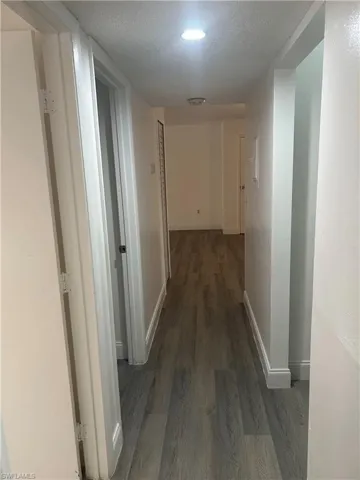 Corridor featuring a textured ceiling and dark wood-style floors