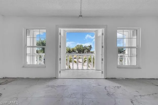 Doorway featuring a textured ceiling and concrete floors