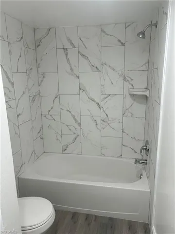 Bathroom with wood finished floors and shower / washtub combination